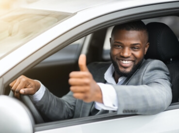 Gentleman with thumbs up all smiles in his car after getting the CIC motor insurance