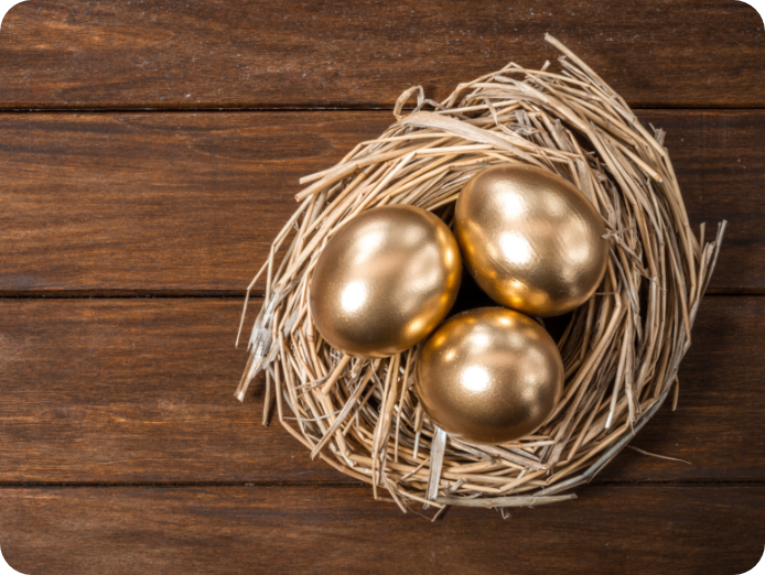Three Golden eggs in a nest on a wooden surface